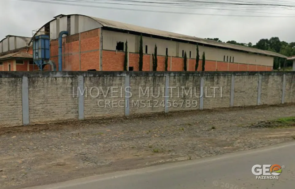 Galpão industrial com muro e estrada de chão
